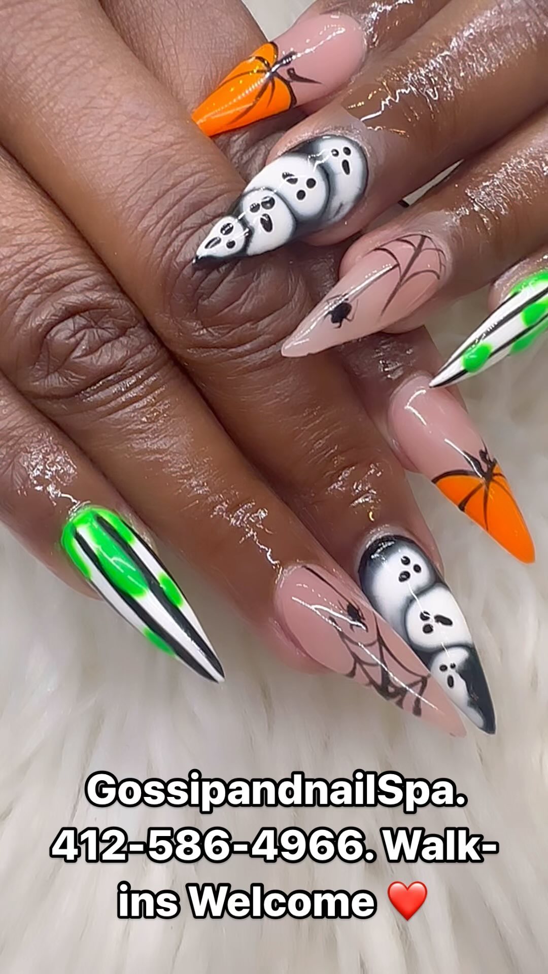 Stiletto nails with airbrushed ghosts, orange pumpkins, spiderwebs and green-and-black stripes